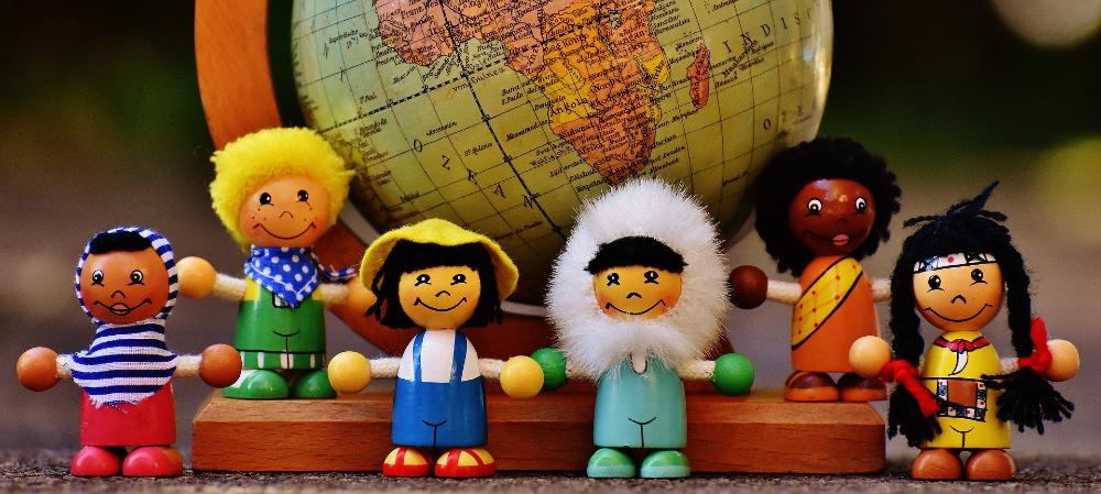 Karttapallo jonka edessä eri kansallisuuksiin puettuja nukkeja.