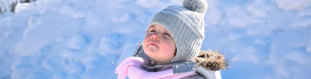 Lapsi katselee taivaalle talvisessa maisemassa.
